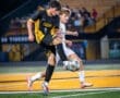 High school soccer players compete for the ball under stadium lights during an intense match, showcasing athleticism.