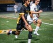 Two soccer players sprinting on the field during a night match, showcasing athleticism and competitive spirit.