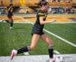 A soccer player dribbles the ball during a game on a sunny day, showcasing agility and skill on the turf field.