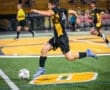 A young soccer player dribbles the ball on a field during a night game, showcasing agility and focus.