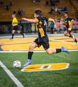A young soccer player dribbles the ball on a field during a night game, showcasing agility and focus.