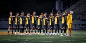 Soccer team standing in formation on the field, showing teamwork and sportsmanship before a match.