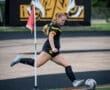 Athlete performing a corner kick in soccer, with a focus on precision and technique. Team colors visible.