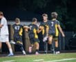Soccer players celebrating a goal under stadium lights, showcasing teamwork and excitement during a night game.