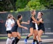 Girls' soccer team celebrating a goal on the field, showcasing excitement and teamwork during a match.
