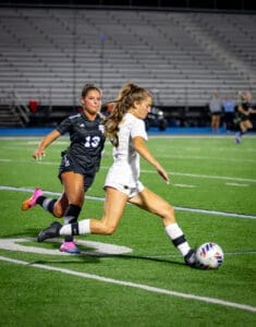 Two soccer players competing for the ball on a night field, showcasing athleticism and teamwork in action.