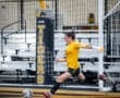 Goalkeeper in yellow uniform kicks soccer ball during a game, showcasing athleticism on the field.