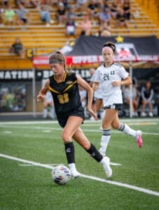 High school soccer players compete on the field, showcasing athleticism and teamwork during a match.