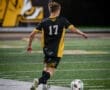Soccer player wearing jersey number 17 prepares to kick a ball on a well-lit field during a match.