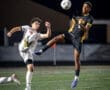 Two soccer players compete for the ball during a night game, showcasing athleticism and dynamic movements on the field.