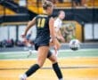 Female soccer player in black jersey #19 skillfully dribbling a ball on the field during a match.