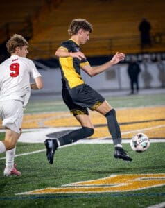 Soccer players compete for the ball on the field during a night match, showcasing action and athleticism.