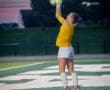 Goalkeeper leaping to catch a soccer ball during a match at dusk, showcasing athleticism and skill on the field.