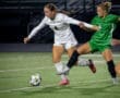 Soccer players compete for the ball on the field during a night match, showcasing athletic skill and teamwork.