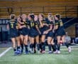 Celebrating players from the Tigers soccer team joyful after scoring a goal during a night game.