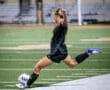 Soccer player in action, kicking a ball on the field during a night match, showcasing athleticism and skill.