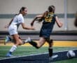 High school soccer players compete for the ball under night lights, showcasing athleticism and teamwork on the field.