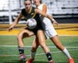 Two female soccer players compete for the ball under stadium lights, showcasing athleticism and competitive spirit.