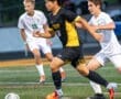 High school soccer match featuring players in action, one sprinting with the ball while opponents chase.
