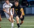 Two young soccer players compete for the ball on the field during a game, showcasing skill and athleticism.