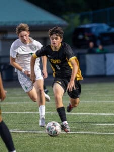 Two young soccer players compete for the ball on the field during a game, showcasing skill and athleticism.