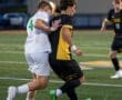 Two soccer players compete for the ball during a match, showcasing speed and athleticism on the field.