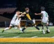 High school soccer players compete under stadium lights, showcasing dynamic action and athleticism on the field.
