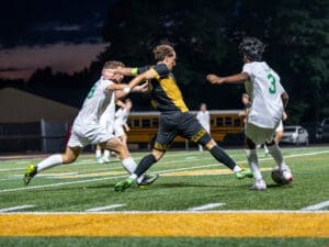 High school soccer players compete under stadium lights, showcasing dynamic action and athleticism on the field.