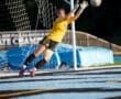 Goalkeeper leaps to save a shot during a soccer match, showcasing agility and focus on the field.