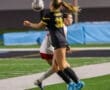 Soccer players compete for the ball during an intense night match on a well-lit field.