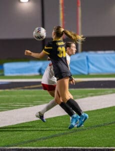 Soccer players compete for the ball during an intense night match on a well-lit field.