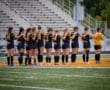 Team of female soccer players standing in formation on the field, showing unity before the game.