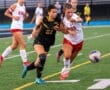 Two female soccer players fiercely compete for the ball on a field, showcasing athleticism and teamwork during a match.