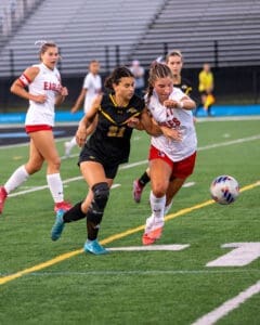 Two female soccer players fiercely compete for the ball on a field, showcasing athleticism and teamwork during a match.