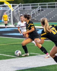 Soccer players compete on the field; one dribbles the ball while opponents strategize. Exciting sports action captured!