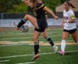Female soccer player skillfully juggling the ball on a grassy field, showcasing athleticism and teamwork during a match.