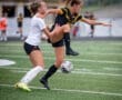 Two female soccer players compete for the ball on a field, showcasing intense action and athleticism during a match.