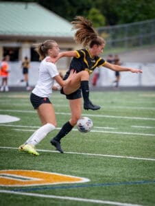 Two female soccer players compete for the ball on a field, showcasing intense action and athleticism during a match.