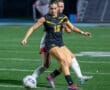 Soccer players compete for the ball on a brightly lit field, showcasing athleticism and teamwork during the game.