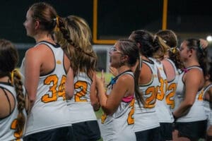 Cheerleaders in team jerseys celebrate and cheer during a night game, showcasing excitement and team spirit.