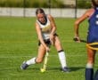 Field hockey player skillfully dribbling the ball on the artificial turf during an intense game.