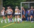 Field hockey players celebrate a goal during a match, showcasing teamwork and sportsmanship on the turf.