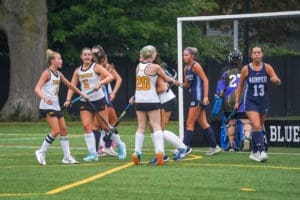 Field hockey players celebrate a goal during a match, showcasing teamwork and sportsmanship on the turf.