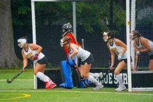 Field hockey players prepare for action during a match, showcasing teamwork and athleticism on the turf.