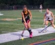 High school field hockey players compete under stadium lights, showcasing skill and determination on a turf field.