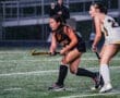 Field hockey players compete in the rain, showcasing athleticism and determination on the turf.