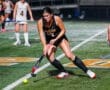 Field hockey player in action, skillfully dribbling the ball during a night game. Team Tigers competing on the field.