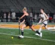 High school field hockey players compete under stadium lights, showcasing skill and athleticism on the turf.