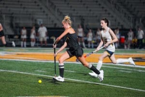 High school field hockey players compete under stadium lights, showcasing skill and athleticism on the turf.