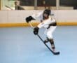 Young hockey player in motion, skillfully maneuvering on a blue rink during a roller hockey game.